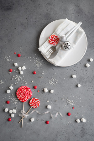 Christmas table setting with red and white seasonal winter sweets on gray, copy space. Christmas dinner, party desigh, concept.の写真素材