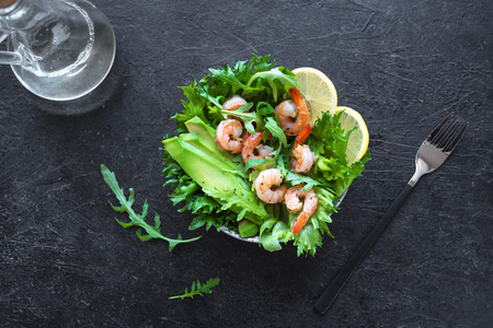 Avocado Shrimp Salad on black stone background, copy space. Healthy diet green salad with Shrimps (prawns), avocado and arugula.の写真素材