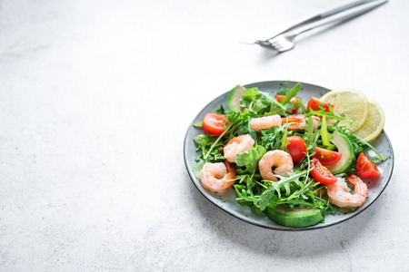 Avocado Shrimp Arugula Salad on white stone background, copy space. Healthy diet green salad with Shrimps (prawns), avocado and arugula.の写真素材