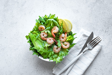 Avocado Shrimp Salad on grey stone background, copy space. Healthy diet green salad with Shrimps (prawns), avocado and arugula.の写真素材