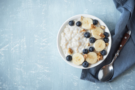 Oatmeal porridge with walnuts, blueberries and banana in bowl - healthy organic breakfast, oats with fruits, honey and nuts.の写真素材