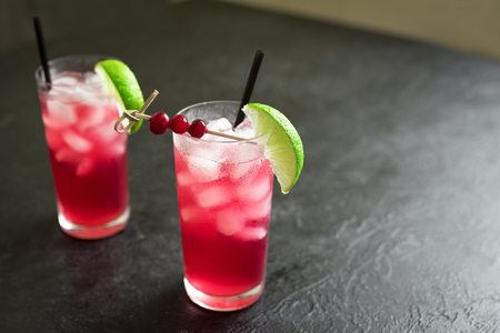 Cranberry Vodka Cocktail with lime and ice on black background, copy space. Cape Codder Cocktail with cranberry juice and vodka, alcohol drink.の写真素材