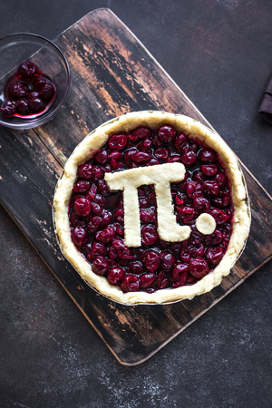 Pi Day Cherry Pie - making homemade traditional Cherry Pie with Pi sign for March 14th holiday, on rustic background, top view.の写真素材