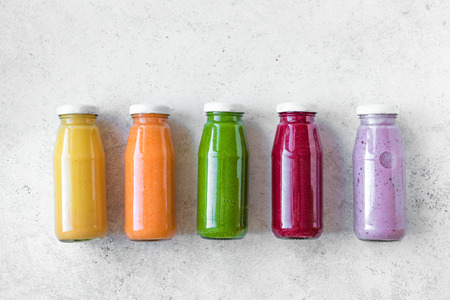 Various smoothies or juices in bottles, healthy diet detox vegan clean food concept, top view, copy space. Colourful smoothies on white background.の写真素材