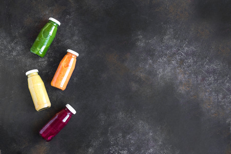 Various smoothies or juices in bottles, healthy diet detox vegan clean food concept, top view, copy space. Colourful smoothies on dark background.の写真素材