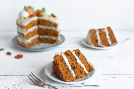 Carrot cake with cream cheese frosting decorated with sugar carrots and pecan nuts. Healthy homemade...