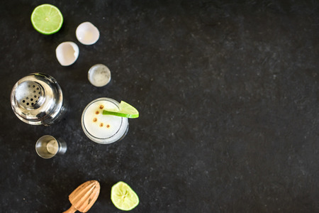 Pisco Sour Cocktail. Peruvian, Mexican, Chilean traditional drink pisco sour liqueur with  lime and egg and bar equipment for making.の写真素材