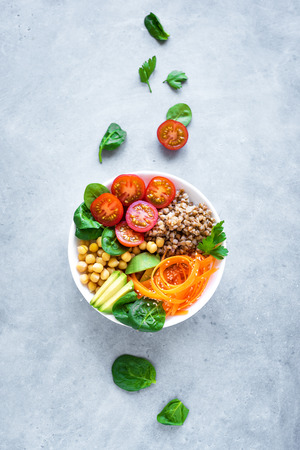 Buddha bowl salad with buckwheat, avocado, carrot, tomato, spinach, chickpea. Healthy vegetarian vegan diet eating, super food. Top view, copy space.の写真素材