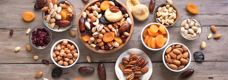 Mixed nuts and dried fruits in wooden bowl on wooden background, top view, banner. Healthy snack - mix of organic nuts and dry fruits.の写真素材