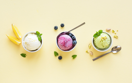 Ice Cream Assortment. Various fruit and berries ice creams on yellow background, copy space. Frozen yogurt or ice cream - healthy summer dessert.の写真素材