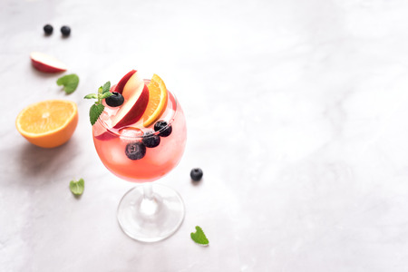 Pink Wine Sangria drink with Fruits and Blueberries on white marble, copy space. Glass of cold summer iced pink sangria cocktail.の写真素材