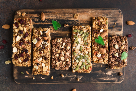 Various granola bars on dark rustic background, top view. Homemade healthy snack - granola superfood bars.の写真素材