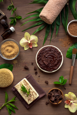 Chocolate Spa composition with plants and flowers, flat lay. Natural spa chocolate cosmetic products and organic treatment concept on dark wooden background.の写真素材