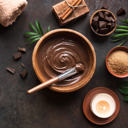 Chocolate Spa flat lay on dark background, top view. Natural chocolate spa beauty products with towel, candle and plants.の写真素材