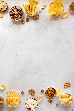 Assortment of Unhealthy Snacks: chips, popcorn, nachos, pretzels, onion rings in bowls, top view, copy space. Unhealthy eating concept.の写真素材