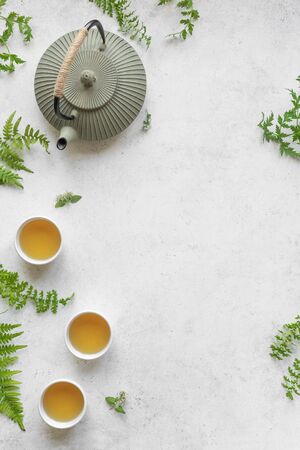 Herbal or Green Tea on white background, top view, copy space. Teapot and teacups with wild plant leaves, natural herbal tea composition.の写真素材