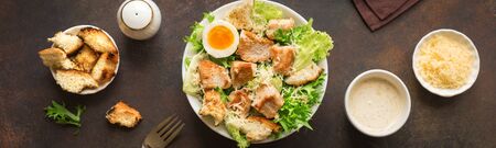 Caesar Salad on dark rustic table, banner, copy space. Homemade chicken caesar salad with grilled croutons.の写真素材