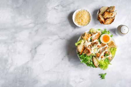 Caesar Salad on marble table, top view, copy space. Homemade chicken caesar salad with grilled croutons.の写真素材