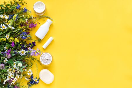 Natural skincare. Cosmetics and organic summer herbs and flowers on yellow background, top view, copy space. Eco friendly and healthy lifestyle concept.の写真素材