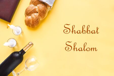 Shabbat or Shabath concept. Challah bread, shabbat wine, book and candles on yellow, top view, copy space. Traditional Jewish Shabbat ritual.の写真素材