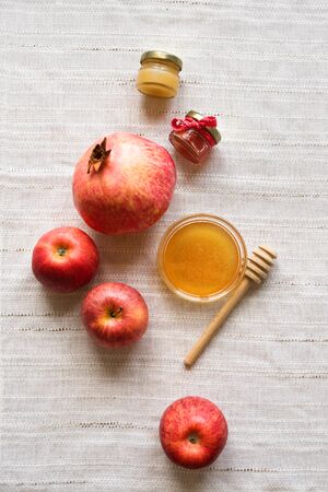 Rosh Hashanah (Jewish New Year holiday) concept. Traditional symbols - apples, honey, pomegranate on white linen background, top view, copy space.の写真素材