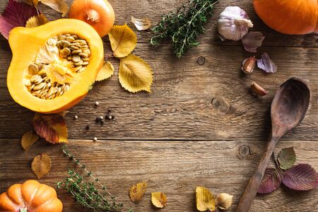 Autumn cooking background. Pumpkin soup ingredients on rustic wooden background, top view, copy space. Pumpkin, spices and autumn leaves.の写真素材