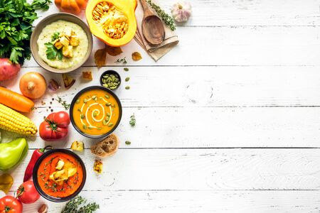 Autumn soups. Set of various seasonal vegetable soups and organic ingredients on white background, top view, copy space. Homemade colourful vegan soups.の写真素材