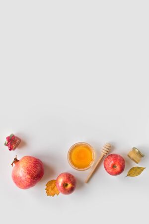 Rosh Hashanah (Jewish New Year holiday) concept. Traditional symbols - apples, honey, pomegranate on white background, top view, copy space.の写真素材