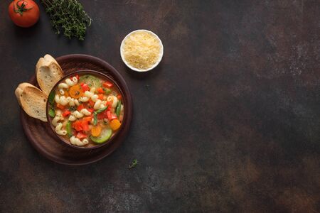 Minestrone Soup. Italian vegetable soup with pasta on dark rustic background, top view, copy space. Healthy vegan vegetarian seasonal meal, homemade minestrone soup.の写真素材