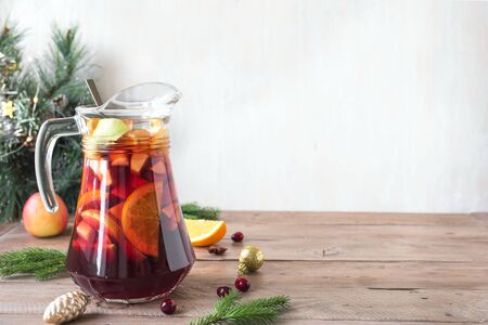 Christmas sangria or punch in pitcher. Homemade red wine fruit sangria and christmas festive decor on wooden background, copy space.の写真素材