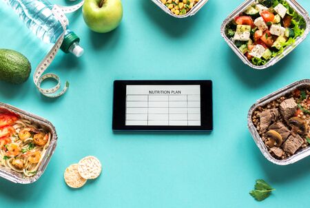 Nutrition plan flat lay with water, fruits, healthy meals and measuring tape. Fitness nutrition, delivery food, daily diet concept on blue, top view, copy space.の写真素材