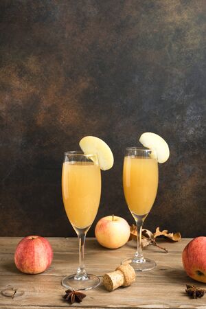 Apple Mimosa Cocktail in tall glasses and organic apples on dark, copy space. Seasonal fall drinks - champagne mimosa cocktail with apples.の写真素材