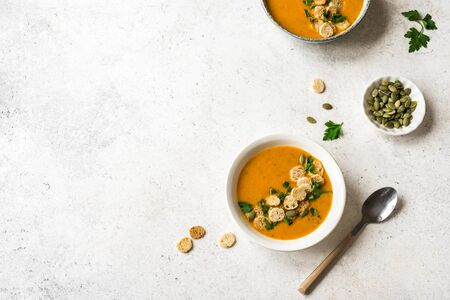 Pumpkin Soup with croutons and parsley in bowls on white background, top view, copy space. Healthy seasonal diet vegetarian food - homemade soup.の写真素材