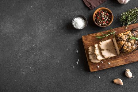 Roasted Pork Meat with herbs and spices on black background, top view. Homemade spicy oven roast...