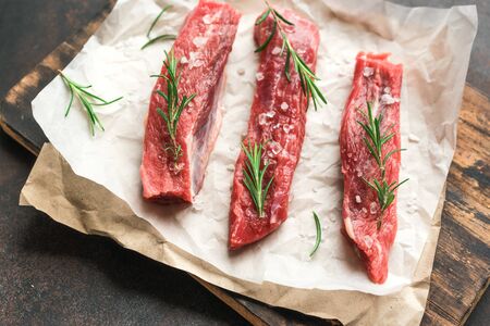 New York Strip Steak with salt and rosemary on black background, top view, close up. Uncooked raw beef strip steaks.の写真素材