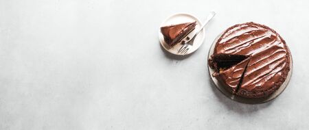 Chocolate cake with cut pieces on light gray background, top view, copy space. Classic chocolate...