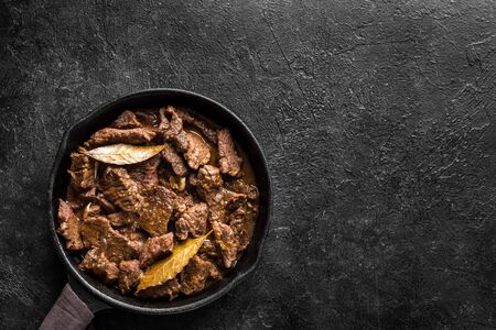 Meat Stew. Beef stewed in red wine sauce, top view, copy space. Roasted beef meat. Braised beef portion meat. Slow cooked meat in cast iron pan.の写真素材