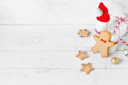Cookies and milk for Santa. Christmas composition with Gingerbread cookies and milk on white wooden background, copy space.の写真素材