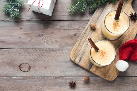 Eggnog Christmas drink with grated nutmeg and cinnamon sticks for Christmas and winter holidays, on wooden background, top view, copy space.の写真素材
