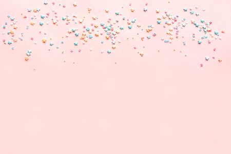 Colorful Pastel Sprinkles on pink background, top view, copy space. Sweet cake pastry ingredient, holiday birthday party and celebration concept, creative border.の写真素材