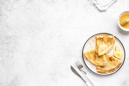 Crepes with Lemon and Honey on white background, top view, copy space. Homemade thin crepes on plate for breakfast or dessert.の写真素材