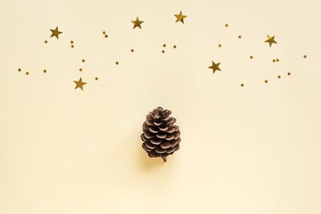 Christmas Composition with pine cone and stars on golden festive background, top view, copy space....