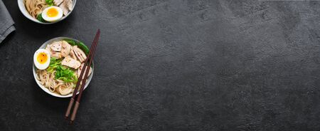 Asian ramen noodles soup with chicken, soft egg and greens on black background. Japanese food, ramen...