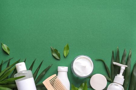 Organic Hair Care products with green leaves on green background, trendy layout, eco beauty and...