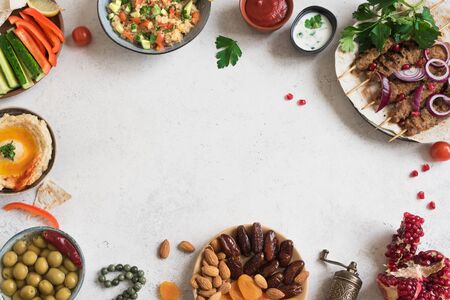Arabic and Middle Eastern food, dinner table. Meat kebab, hummus, tabbouleh salad, traditional sauces, olives, pita,  dates fruits, nuts, pomegranate. Set of Arabian meal, top view, copy space.の写真素材