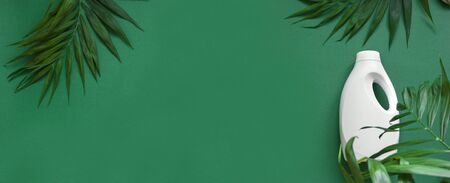 Plastic bottle and green leaves on green background. Recycling pack, eco bio liquid detergent, cleaning agent, antibacterial gel with natural plant extract. Eco lifestyle flat lay, banner, copy space.の写真素材