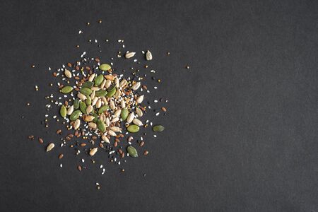 Healthy Seeds Mix for Salads and healthy dishes. Pile of mixed seeds on black background, top view, copy space.の写真素材