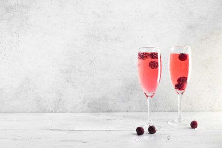 Kir Royal Champagne Cocktail on white, copy space. Flute glasses with berry sparkling champagne drink for celebrating or chilling.の写真素材