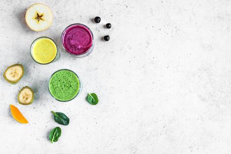 Colorful Smoothie Drinks for healthy detox breakfast, top view, copy space. Three various green, yellow, purple smoothies with ingredients. Vegan raw food, healthy eating concept.の写真素材