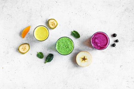Colorful Smoothie Drinks for healthy detox breakfast, top view, copy space. Three various green, yellow, purple smoothies with ingredients. Vegan raw food, healthy eating concept.の写真素材